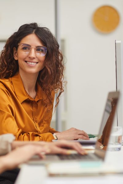 Two beautiful female colleagues interacting while working in office